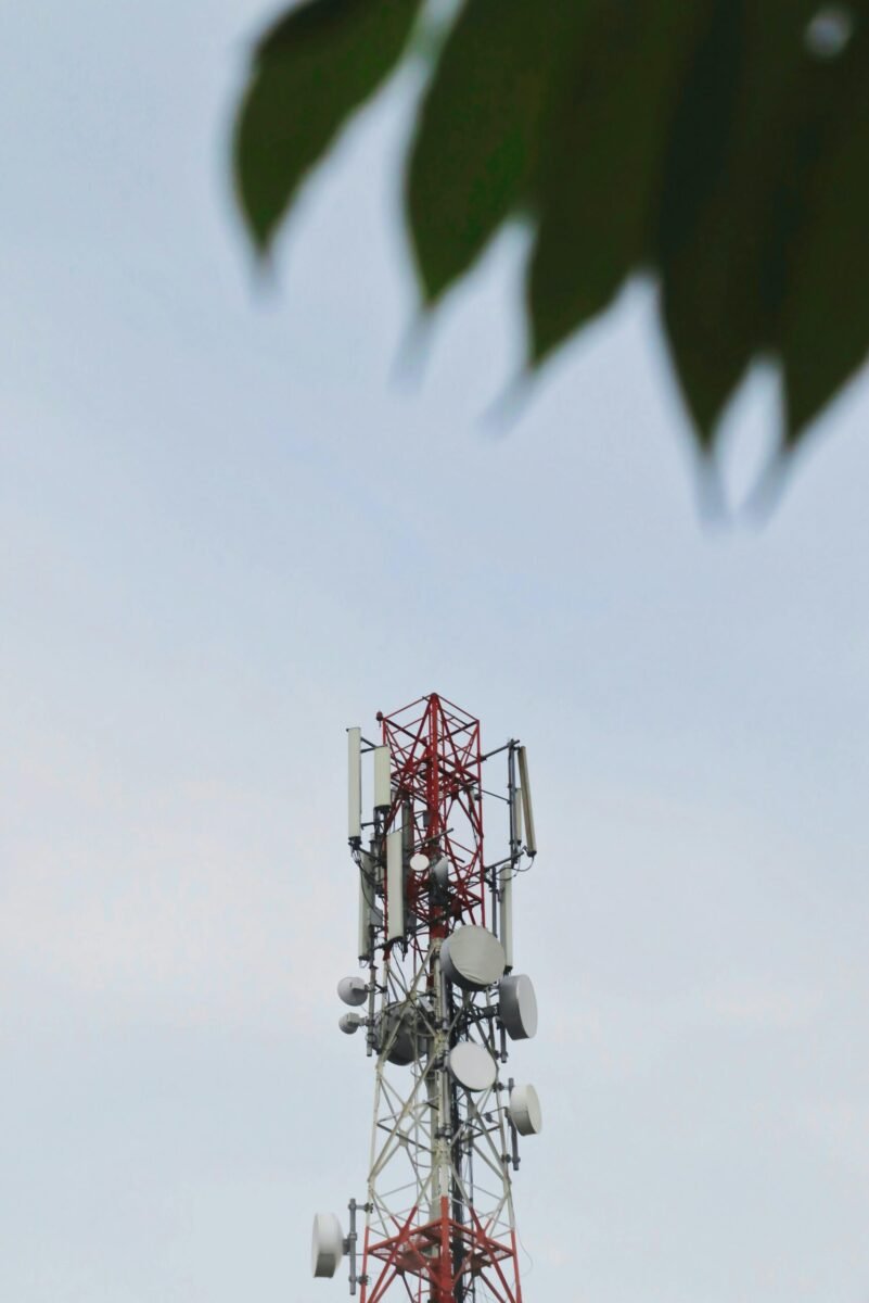 Low angle view of a telecommunication tower with antennae against a clear sky.
